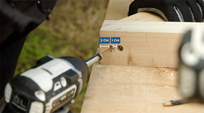 una persona fija los trozos de madera con tornillos.
