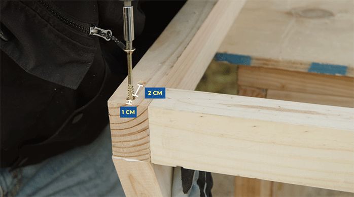 una persona fija una unión de madera con tornillos.