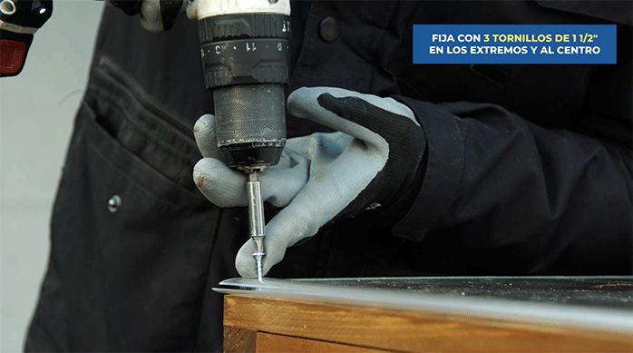 una persona fija el policarbonato alveolar al alero de madera atornillando en los perfiles H.