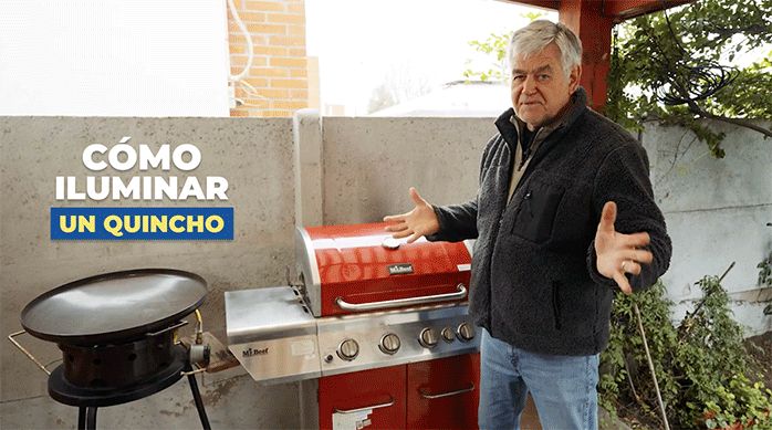 un hombre en un quincho, frente a una parrilla, listo para mostrar cómo iluminar un quincho.
