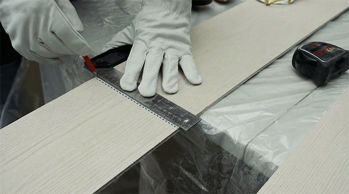 una persona traza una línea en una plancha de siding.
