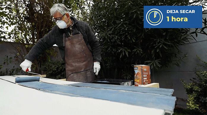 un hombre pinta una plancha de siding de fibrocemento con esmalte.