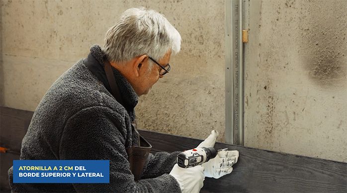 un hombre instala una plancha de siding de fibrocemento.