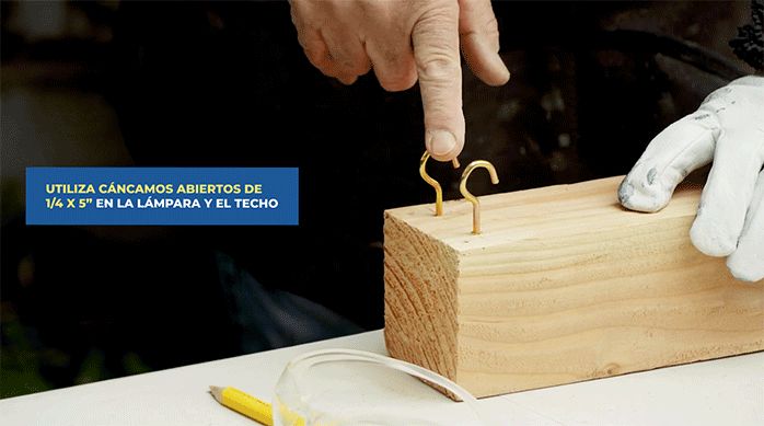 un hombre pone 2 cáncamos en el extremo del trozo de madera.