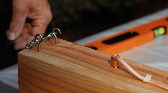 un trozo de madera con cáncamos y una luz recién instalada.
