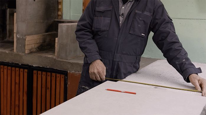 una persona con overol mide el ancho de un mesón en un quincho.