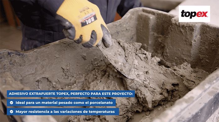 un hombre mezcla adhesivo extrafuerte Topex en una batea con una espátula.