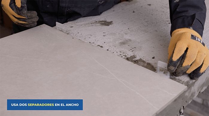 una persona pone separadores entre las planchas de porcelanato.