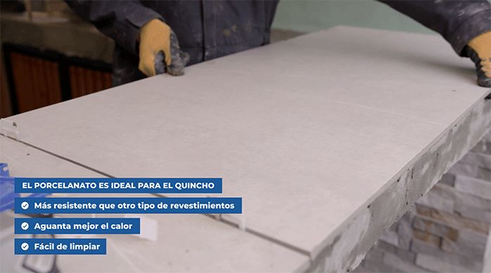 una persona pega una plancha de porcelanato en el mesón de un quincho.