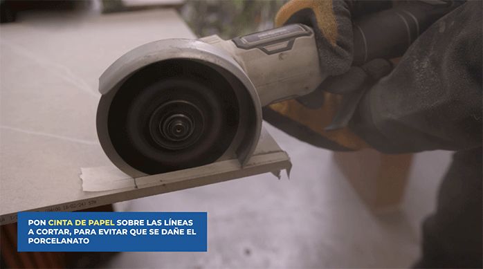 una persona corta un trozo de porcelanato usando un esmeril angular.