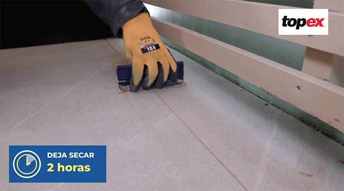 una persona usa una lengüeta de goma para retirar el exceso de fragüe del porcelanato.