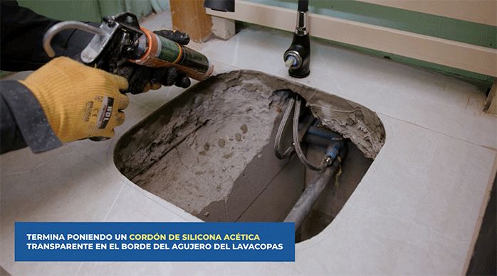 una persona pone un cordón de silicona en el borde del agujero para el lavacopas.
