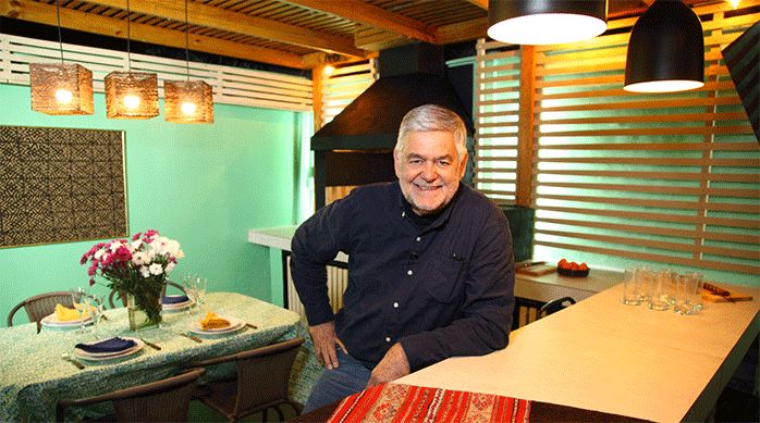 un hombre sentado y apoyado en un mesón recién remodelado con porcelanato, en un quincho.