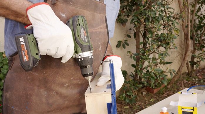 un hombre usa un desatornillador eléctrico para unir dos trozos de madera.
