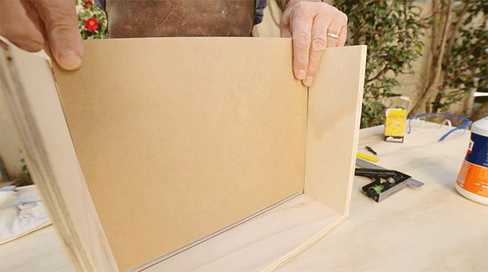una persona introduce el trozo de mdf en las ranuras del cajón para el especiero.
