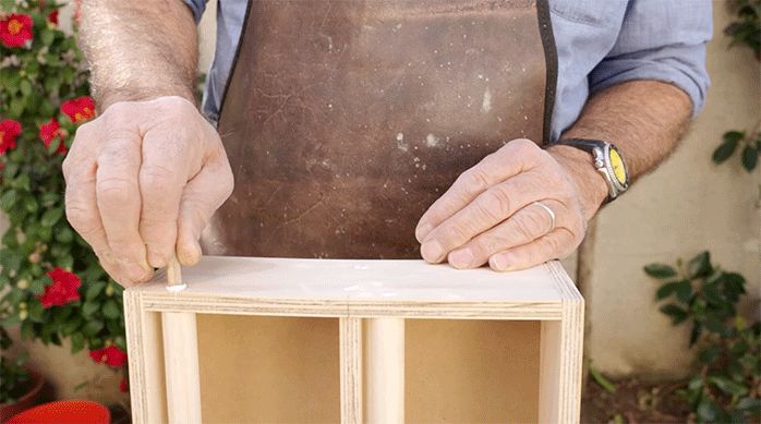 una persona pone tarugos de madera en los tornillos en el especiero colgante para disimularlos.
