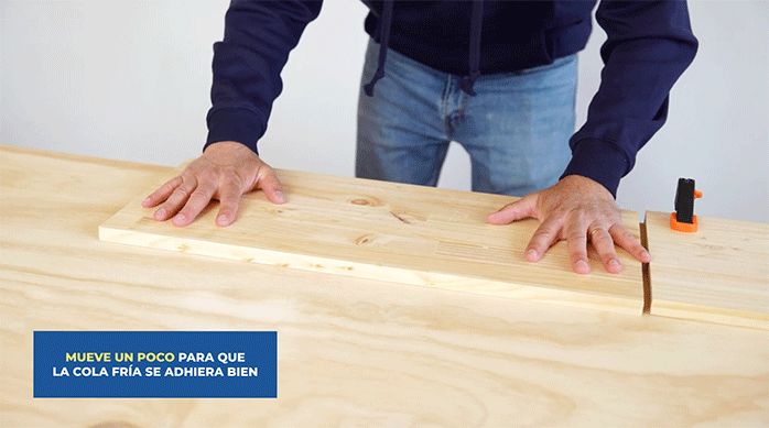 un hombre presiona una repisa laminada de madera sobre la base de terciado para construir el respaldo.