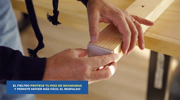 un hombre pega fieltros en las patas del respaldo o cabecera de cama.