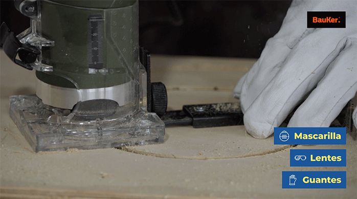 una persona usa una fresadora con guía de corte para cortar un círculo en un trozo de madera.