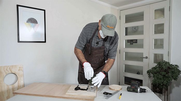 un hombre corta un trozo de madera usando la fresadora.
