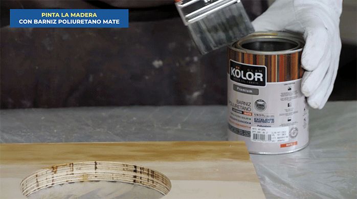 un hombre aplica barniz poliuretano mate usando una brocha en los trozos de madera para hacer la barra plegable.