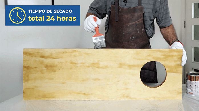 una persona aplica barniz poliuretano mate en un trozo de terciado de mueblería para hacer la barra plegable para terraza.