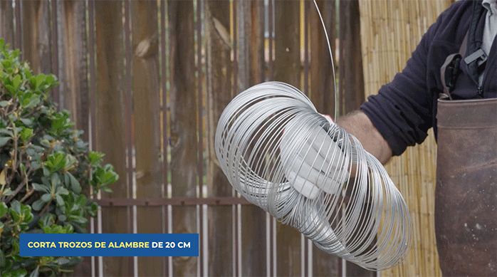 un hombre sostiene un rollo de alambre galvanizado.