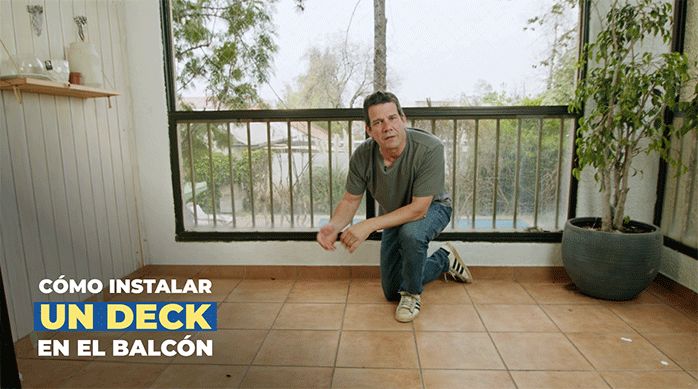 un hombre arrodillado en el piso de un balcón listo para enseñar cómo instalar un deck de madera en el balcón.