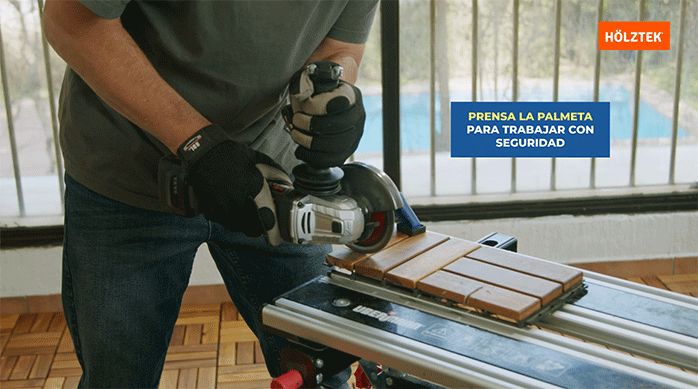 una persona usa un esmeril angular para cortar una palmeta del deck de madera.