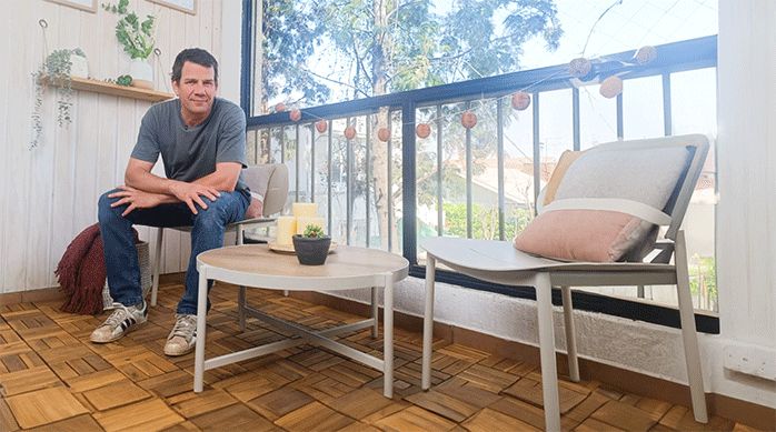 un hombre sentado en un balcón recién remodelado con un deck de madera sobrepuesto.