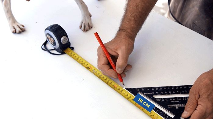 un hombre marca una puerta usando un lápiz y una regla.