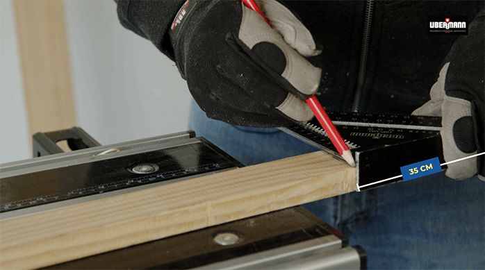 un hombre marca un listón de madera usando un lápiz y una escuadra.