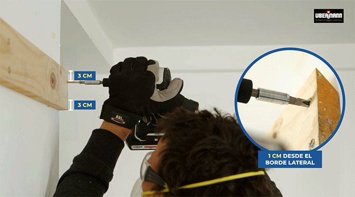 un hombre fija un listón de madera en el muro de cocina usando tornillos.