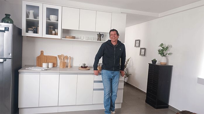 un hombre en una cocina apoyado en los muebles modulares base, frente a unos muebles flotantes recién instalados.