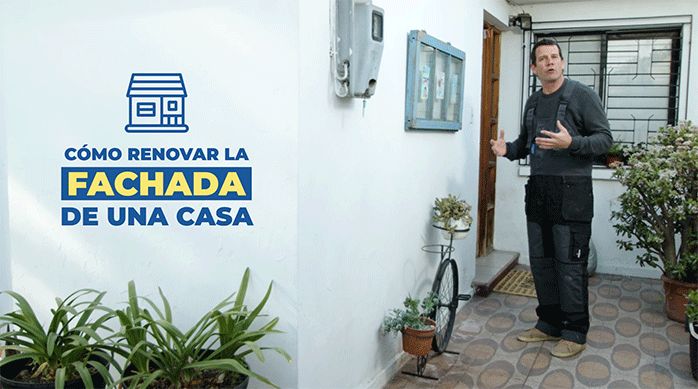 un hombre con overol frente a la fachada de una casa listo para explicar cómo renovar la fachada de una casa con pintura y piedra natural.