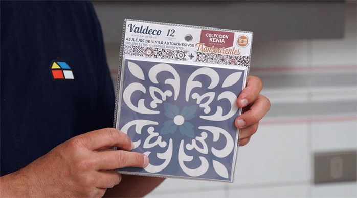 una persona sostiene un sobre de plástico con varios mosaicos adhesivos para renovar una cocina.