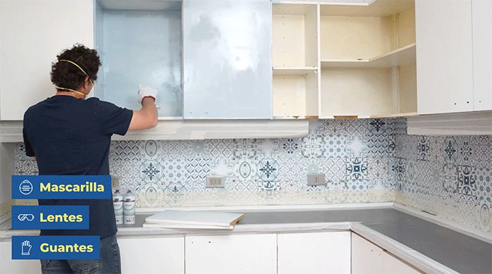 un hombre aplica pintura en spray chalky kölor azul bebé en los muebles de cocina.