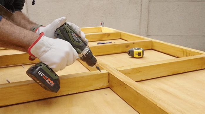 una persona fija un trozo de madera para armar una cuadrícula.
