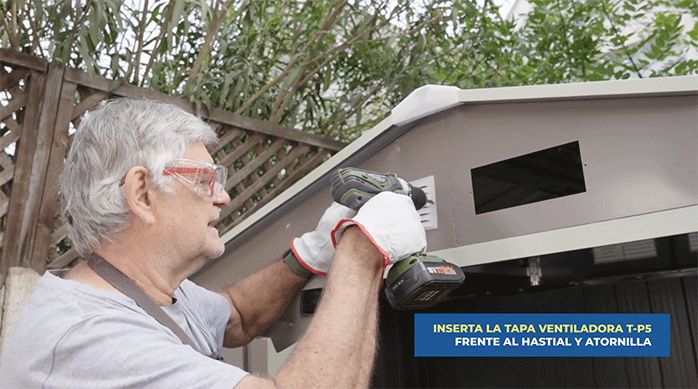 un hombre instala las tapas de ventilación en el hastial de la bodega de jardín.