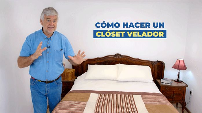 un hombre al lado de una cama de dos plazas listo para enseñar cómo hacer un clóset con veladores.