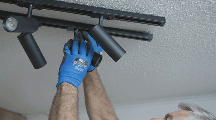 un hombre instala focos led en el cielo de una habitación.