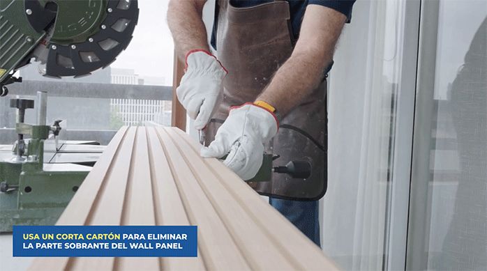 una persona corta el borde de una plancha de wall panel usando un cuchillo cartonero.