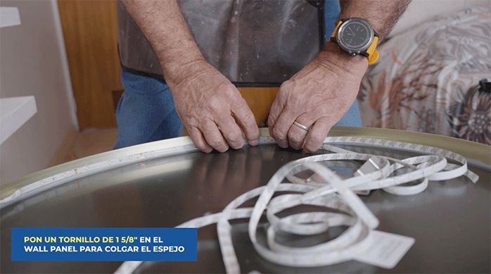 una persona pega una cinta de luces led en la parte posterior de un espejo.