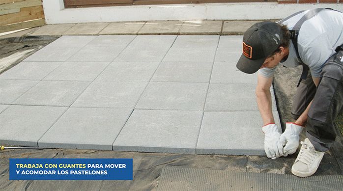 un hombre pone el último pastelón de la terraza de pastelones que armó para el jardín de pasto sintético y piedras.