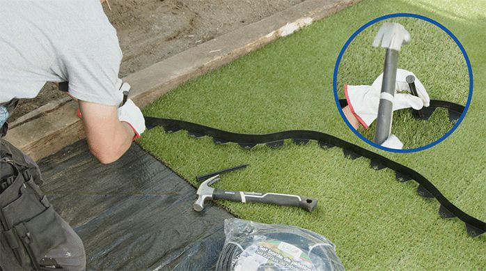 una persona instala un borde plástico para jardín sobre el pasto sintético.