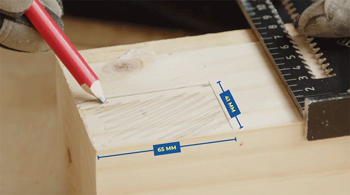 una persona marca con un lápiz el calado que debe hacer en una de las patas de la mesa para juegos.
