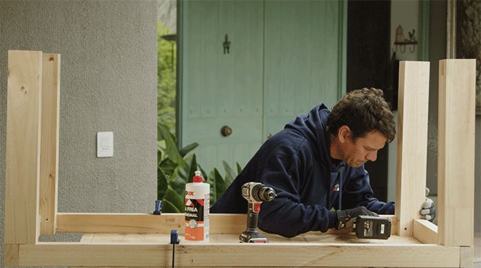 un hombre fija las patas de madera en la estructura base de la mesa para juegos.