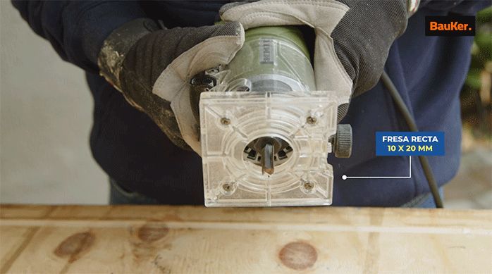 una persona con guantes de seguridad sostiene una fresadora con fresa recta de 10 x 20 mm.