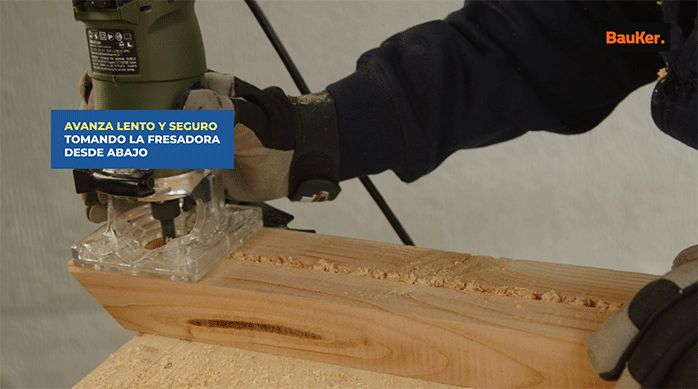 un hombre usa una fresadora para hacer un calado en un trozo de madera.
