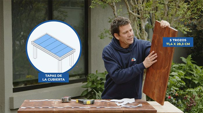 un hombre sostiene un trozo de madera que usará para hacer una cubierta para la mesa para juegos.
